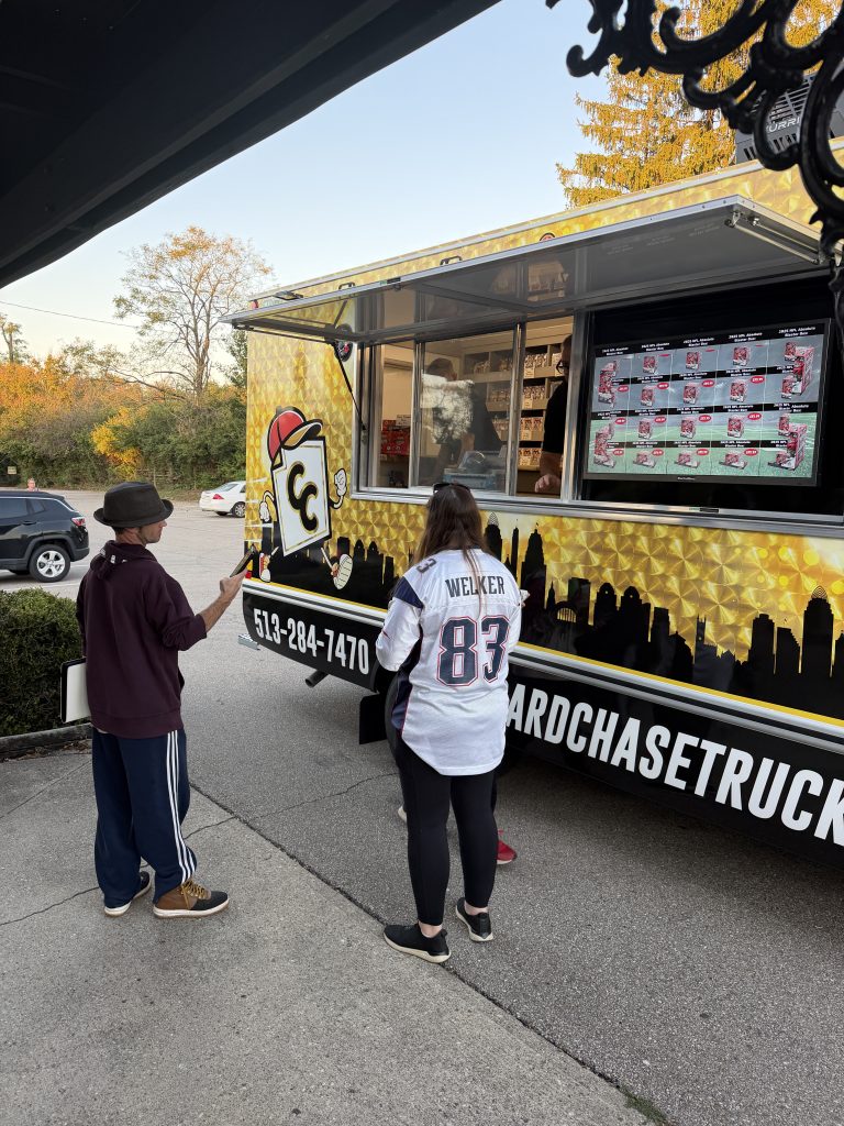 Customers shopping sealed sports card and Pokémon boxes at the Card Chase truck window